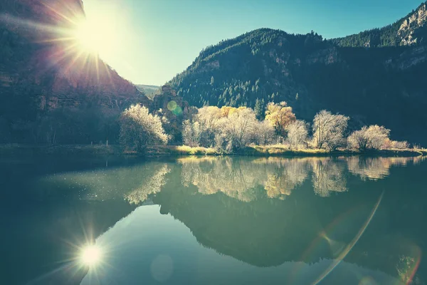 Beautiful mountain lake at sunrise with lens flare effect. — Stock Photo, Image