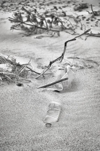 Imagen en blanco y negro de botellas de plástico dejadas en una playa . — Foto de Stock