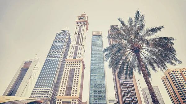 Retro gestileerde panoramische foto van Dubai wolkenkrabbers met een palmboom. — Stockfoto