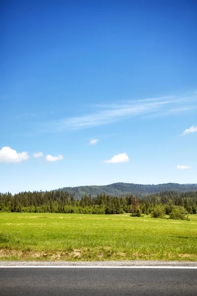 Fältet av en väg med blå himmel och bergskog . — Stockfoto