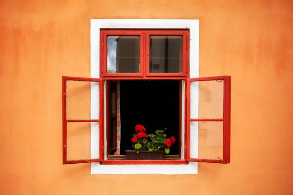 Altes rotes Fenster mit Blumen in orangefarbener Wand geöffnet — Stockfoto
