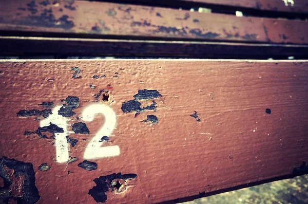 Номер двенадцать нарисован на старом деревянном сидении . — стоковое фото