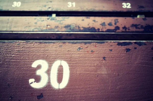 Número trinta pintado em um assento de madeira velho . — Fotografia de Stock