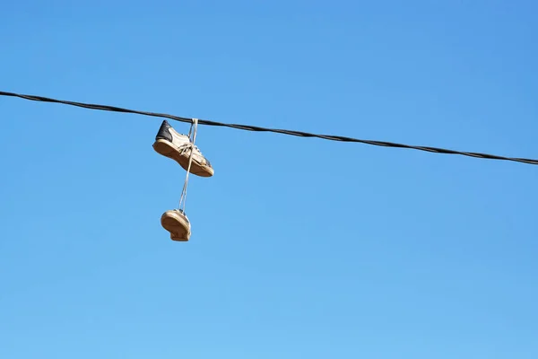 Par de sapatos velhos pendurados na linha de energia . — Fotografia de Stock