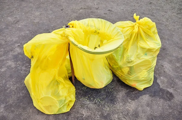 Leaking yellow plastic garbage bags on camping ground.