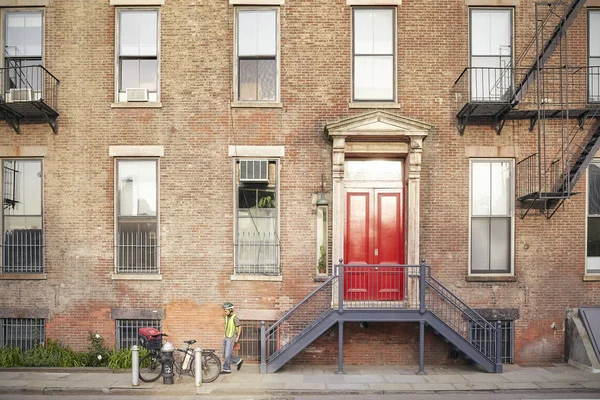 Joven en bicicleta frente al típico apartamento de Nueva York . — Foto de Stock