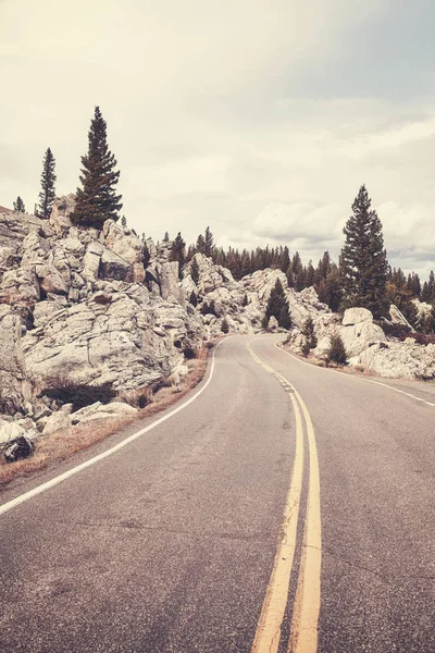 Vintage toned scenic mountain road in Yellowstone National Park. — Stock Photo, Image