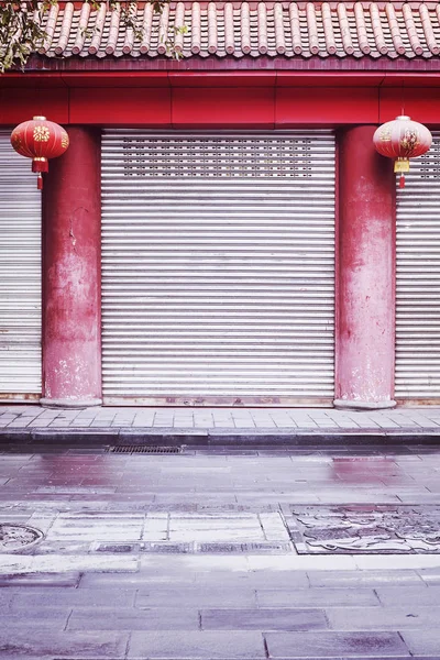 Closed shop facade with red columns and lanterns, China. — Stock Photo, Image