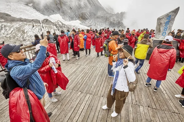 Tourists on the Jade Dragon Snow Mountain viewing platform covered with clouds. — Stock Photo, Image