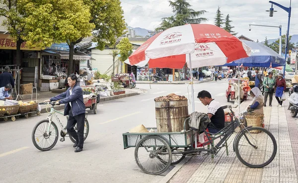 Food vendor waits for customers with a bicycle stall on a street of Lijiang. — Stock Photo, Image