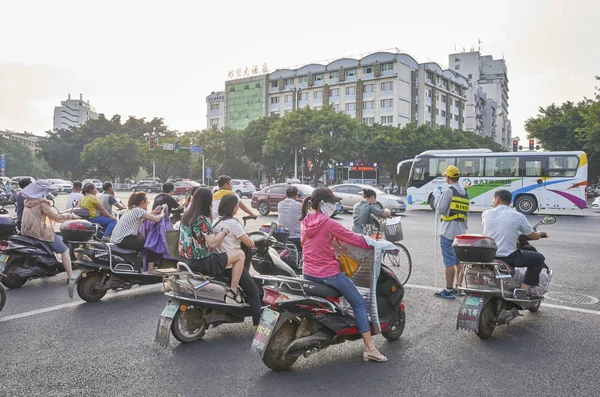 Scooters drivers wait for green light on an intersection in downtown Guilin at sunrise. — Stock Photo, Image