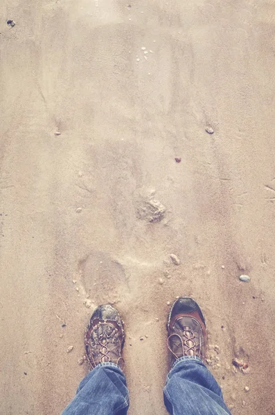 Person i vandrings skor står på en strand. — Stockfoto
