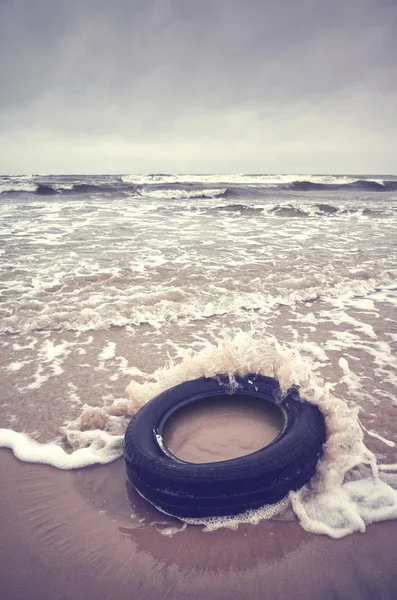Velho pneu de borracha preta deixada em uma praia, poluição ambiental con — Fotografia de Stock