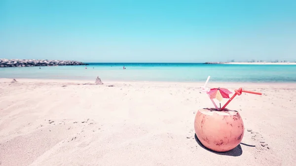 Ρόφημα καρύδας με ομπρέλα και δύο καλαμάκια σε μια παραλία. — Φωτογραφία Αρχείου