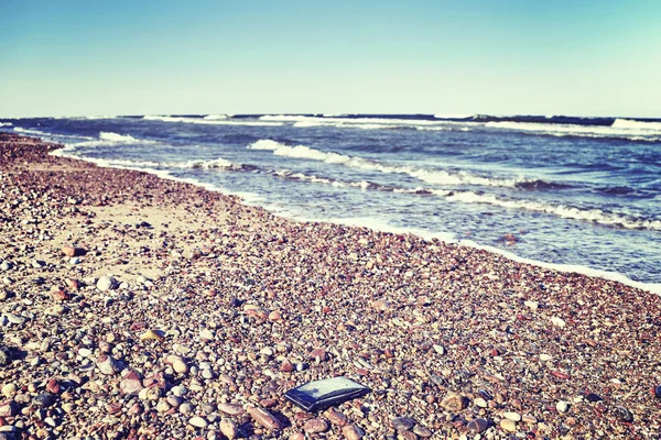 Trasiga mobiltelefon på en stenig strand. — Stockfoto