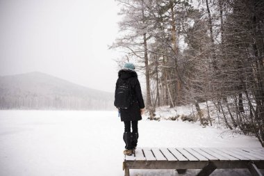 Kış dağlarının arkasında sırt çantalı bir kız. Seyahat, turizm, tatil..