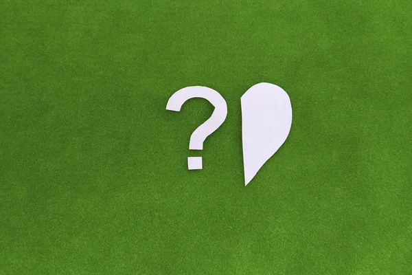 Half of the heart, a question mark on a green background. the concept of finding a second half, a loved one. Relationships, social issues, psychology.