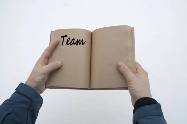 a book with the word Team on the pages in the hands of a person.