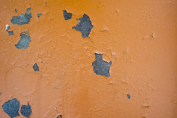 The texture of a sheet of iron painted with orange paint, cracked with time.