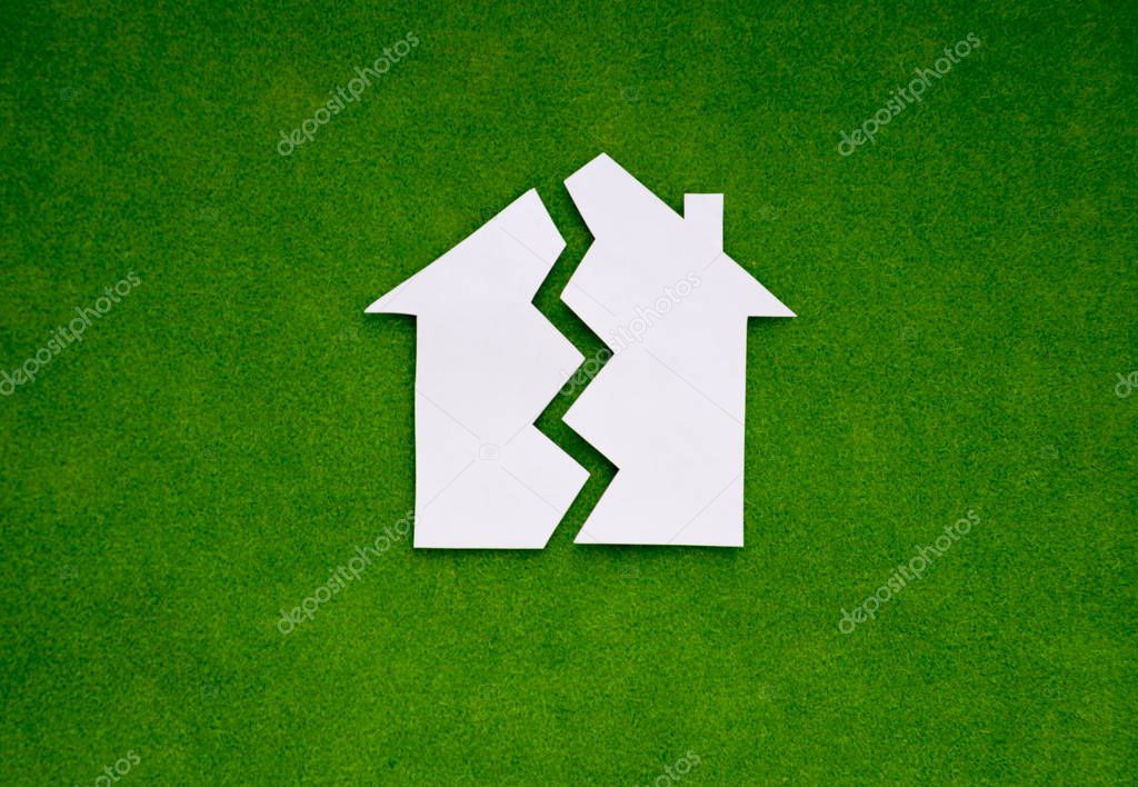 two halves of the house made of white paper on a green background. the concept of property, the real estate market.