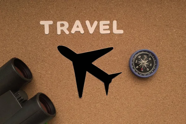 Airplane, compass, binoculars on a brown background. Travel, tourism, outdoor activities.