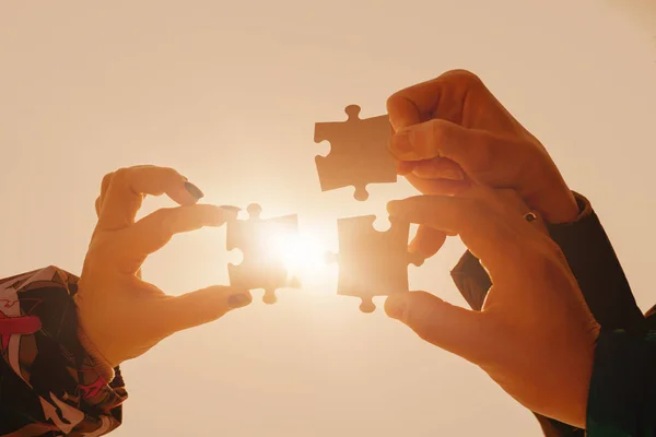 puzzles in the hands of people in the sun. the concept of team, collective thinking, interaction.