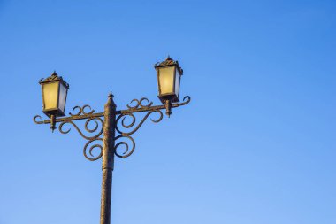 Mavi gökyüzüne karşı iki sokak lambası. Şehir mimarisi. Yapay ışıklandırma.