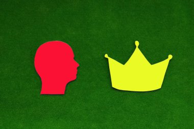 İnsan kafası silueti, mavi renk, yeşil arka planda sarı taç. Güç arzusu.