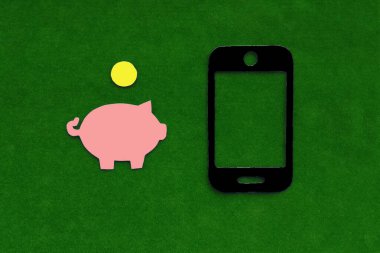 Piggy Bank, yeşil arka planda siyah cep telefonu. Finans, cep harçlığı.