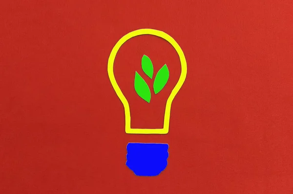 A light bulb with leaves of a plant inside on a red background. Ideas, creativity.