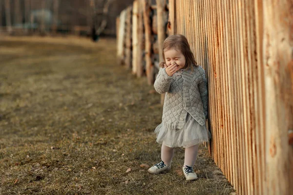 Schattig klein meisje permanent in de buurt van een hek — Stockfoto
