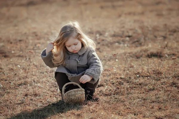 Ein nettes kleines trauriges Mädchen steht am Zaun. — Stockfoto