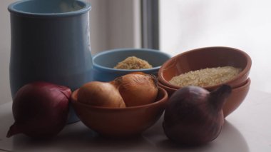Camın arkasında kil sürahiler, mısır gevreği, soğan ve sarımsak var.