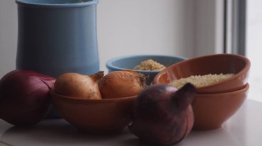 Camın arkasında kil sürahiler, mısır gevreği, soğan ve sarımsak var.