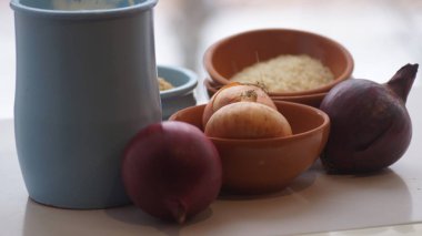 Camın arkasında kil sürahiler, mısır gevreği, soğan ve sarımsak var.