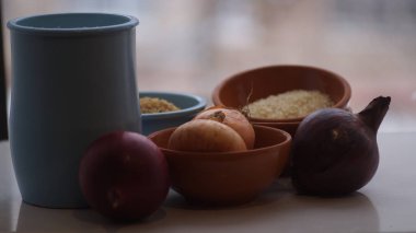 Camın arkasında kil sürahiler, mısır gevreği, soğan ve sarımsak var.