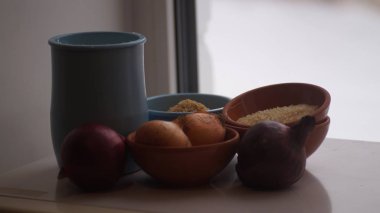 Camın arkasında kil sürahiler, mısır gevreği, soğan ve sarımsak var.