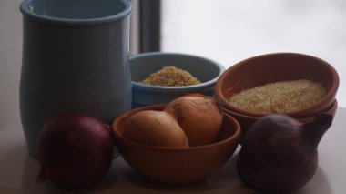 Camın arkasında kil sürahiler, mısır gevreği, soğan ve sarımsak var.