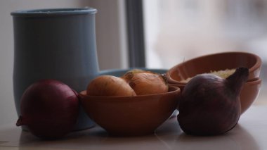 Camın arkasında kil sürahiler, mısır gevreği, soğan ve sarımsak var.