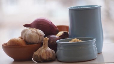 Camın arkasında kil sürahiler, mısır gevreği, soğan ve sarımsak var.