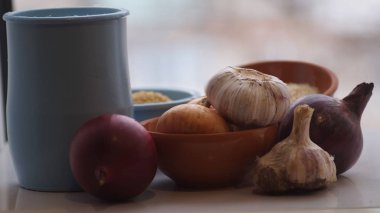 Camın arkasında kil sürahiler, mısır gevreği, soğan ve sarımsak var.