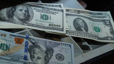 Koyu bir arka planda, bir cüzdanda, bir çekmecede birikmiş Amerikan doları.