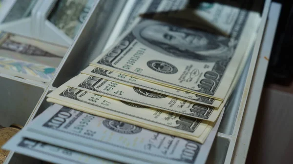 American dollars stacked on a dark background, in a wallet, in a cash drawer