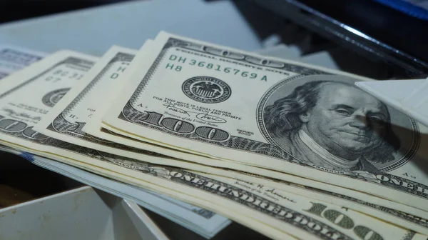 American dollars stacked on a dark background, in a wallet, in a cash drawer