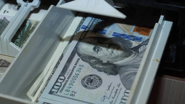 American dollars stacked on a dark background, in a wallet, in a cash drawer