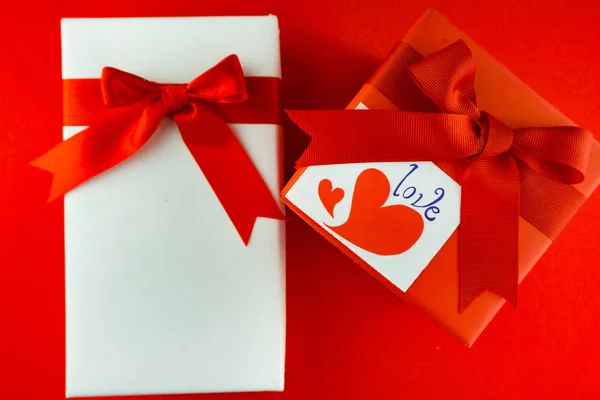 Valentýna dárkové krabičce s červenou mašlí na červeném pozadí obrázek z Va — Stock fotografie