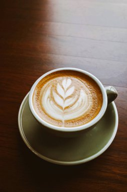 Yakın plan kahve, odun kenarındaki taze süt köpüğünden bırakılmış latte..
