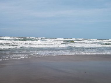 Baltık Denizi 'nde fırtına, kumlu sahil, berrak gökyüzü, bükülmüş dalgalar.