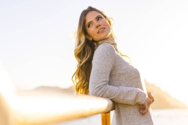 Deniz kıyısında genç ve güzel bir kadının günbatımı portresi.