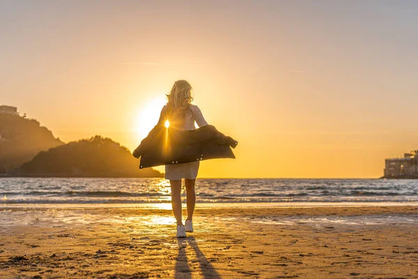 Deniz kıyısında genç ve güzel bir kadının günbatımı portresi.